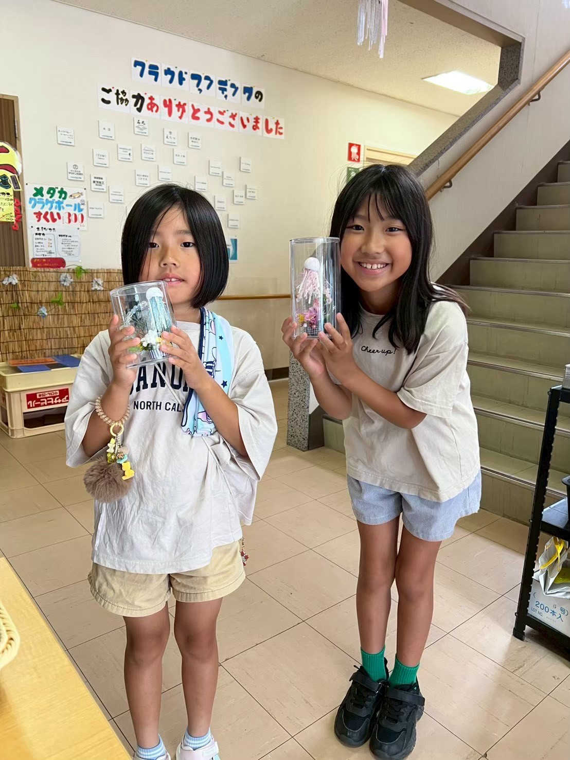 つくった作品を手に並ぶ、ふたりの子ども