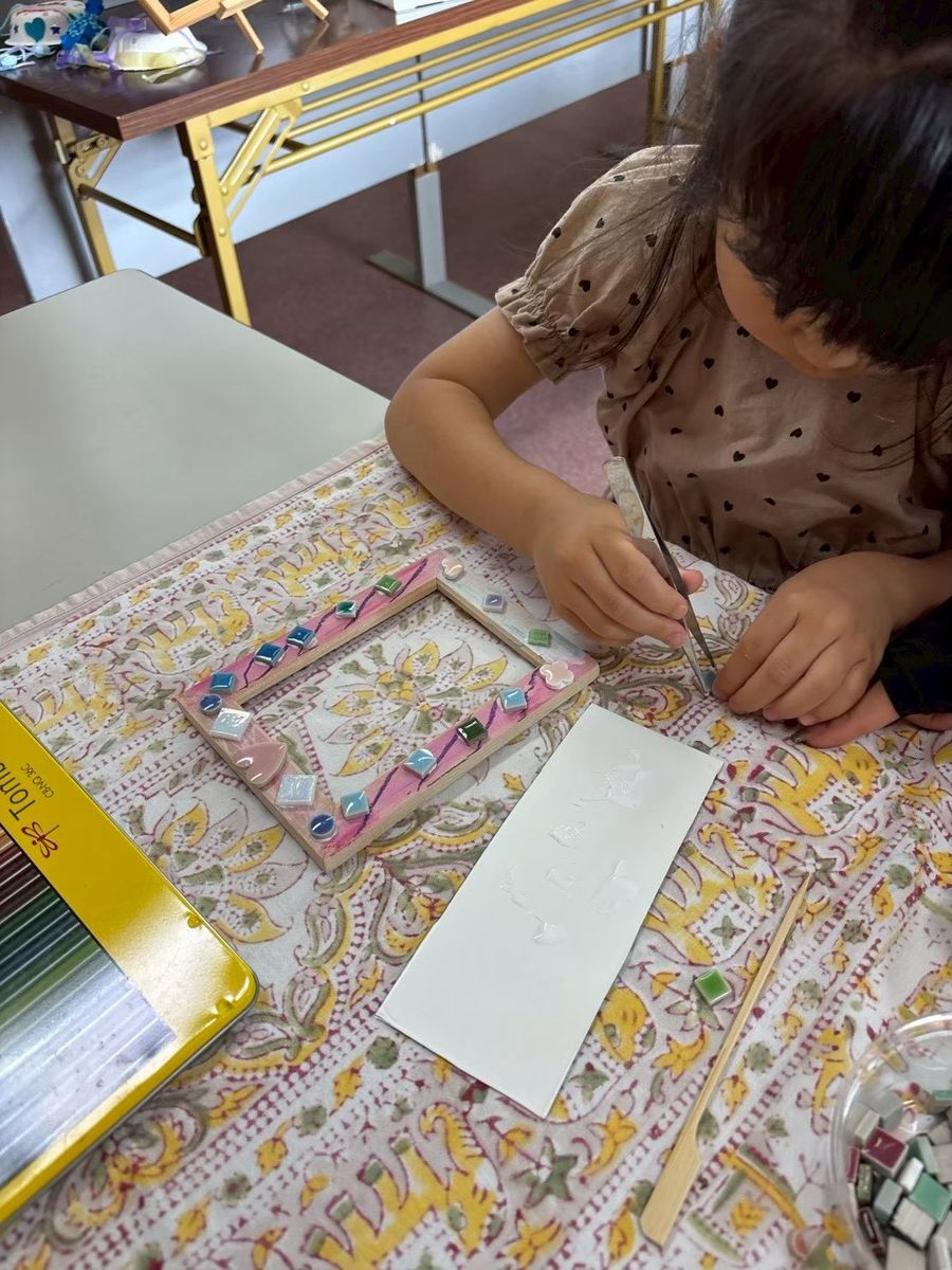 工作室で、フレームに素材を貼りつける子ども